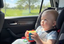 Viaggi lunghi in auto con bambini piccoli: come gestire fame, orari e tappe neonato seduto sul seggiolino in auto