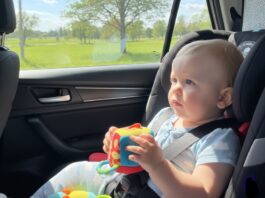 Viaggi lunghi in auto con bambini piccoli: come gestire fame, orari e tappe neonato seduto sul seggiolino in auto