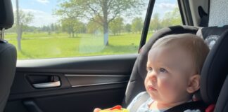 Viaggi lunghi in auto con bambini piccoli: come gestire fame, orari e tappe neonato seduto sul seggiolino in auto